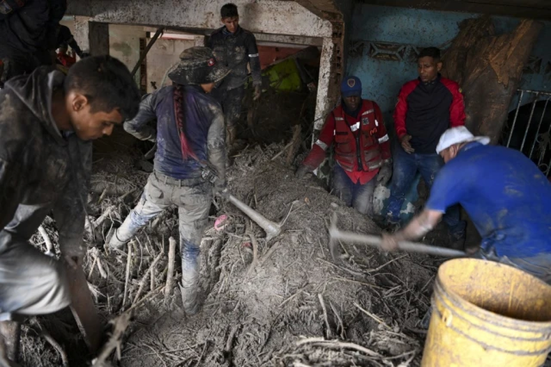 Los residentes ayudan a los rescatistas a desenterrar el lodo de las casas destruidas mientras buscan víctimas o sobrevivientes de un deslizamiento de tierra durante las fuertes lluvias en Las Tejerias, estado de Aragua, Venezuela, el 9 de octubre de 2