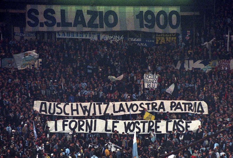 Seguidores de la Lazio despliegan desde las gradas banderas que indican Auschwitz es tu casa. Los hornos son tu casa durante un partido de Serie A entre Lazio y Roma, en el estadio Olímpico, el 29 de noviembre de 1998. (AP Foto/Plinio Lepri, archivo)