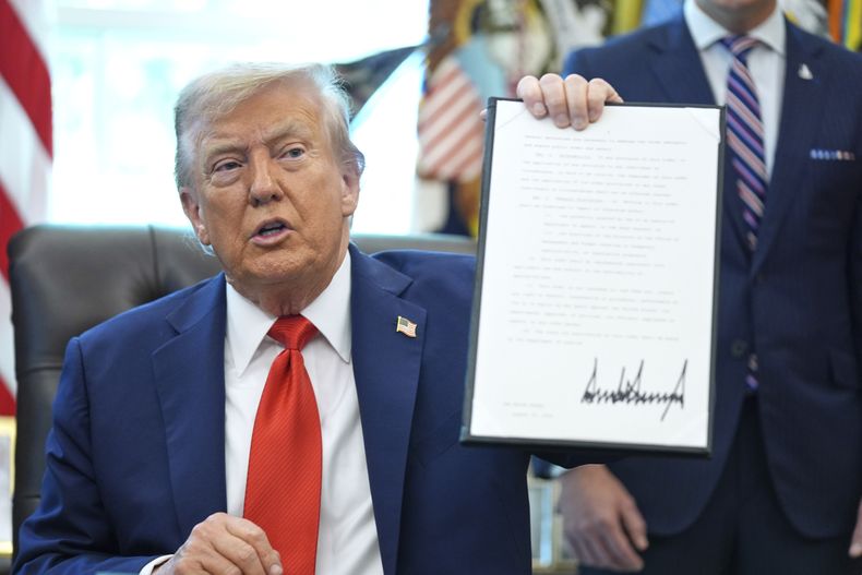 El presidente Donald Trump sostiene una orden ejecutiva firmada que requiere que el Departamento de Justicia investigue los casos de quema de banderas, en la Oficina Oval de la Casa Blanca, el lunes 25 de agosto de 2025, en Washington. (AP Foto/Evan Vucci)