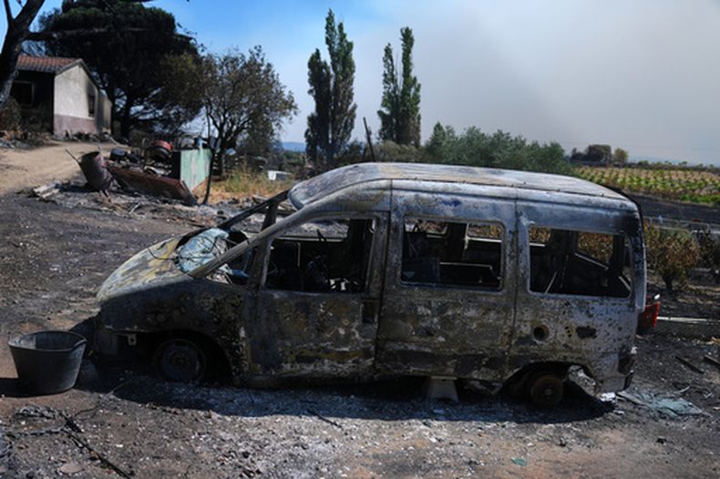Un vehículo calcinado yace frente a una casa en ruinas el domingo 26 de julio de 2026, en Navas del Rey, al oeste de Madrid, España, donde los incendios forestales han obligado a evacuar a decenas de miles de personas. (AP Foto/Manu Fernández)