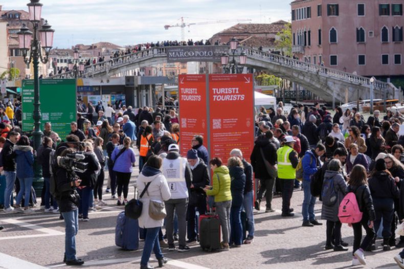ARCHIVO – Varios asistentes verifican los códigos QR de acceso fuera de la principal estación de trenes de Venecia, Italia, el 25 de abril de 2024. El nuevo alcalde de la ciudad propone un sistema de precios dinámicos para la tarifa de acceso para viajeros de un día, vigente desde hace tres años, y busca la aprobación del gobierno para aumentar el precio hasta 50 euros (59 dólares) en los días más concurridos para aliviar la saturación en la ciudad, patrimonio de la UNESCO. (AP Foto/Luca Bruno)