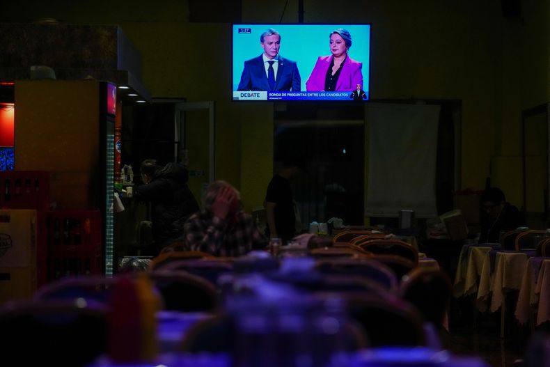 Una pantalla de televisión en un restaurante muestra a los candidatos presidenciales José Antonio Kast, a la izquierda, del Partido Republicano, y Jeannette Jara, de la coalición de gobierno Unidos por Chile, debatiendo en Santiago de Chile el miércoles 10 de septiembre de 2025, antes de las elecciones del país del 16 de noviembre. (AP Foto/Esteban Félix)