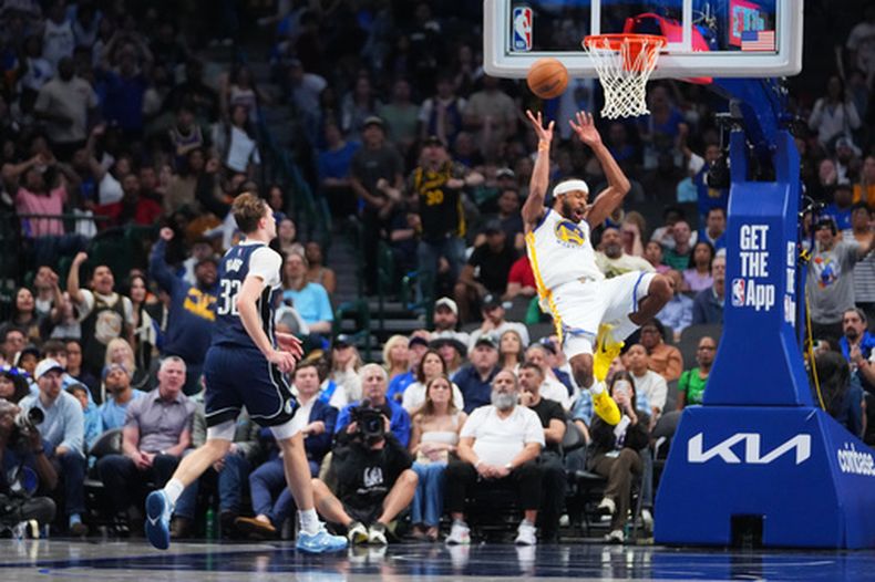 Moses Moody, derecha, de los Warriors de Golden State, reacciona tras sufrir una lesión mientras Cooper Flagg (32), de los Mavericks de Dallas, observa durante el tiempo extra del juego de baloncesto de la NBA, el lunes 23 de marzo de 2026, en Dallas. (AP Foto/Julio Cortez)
