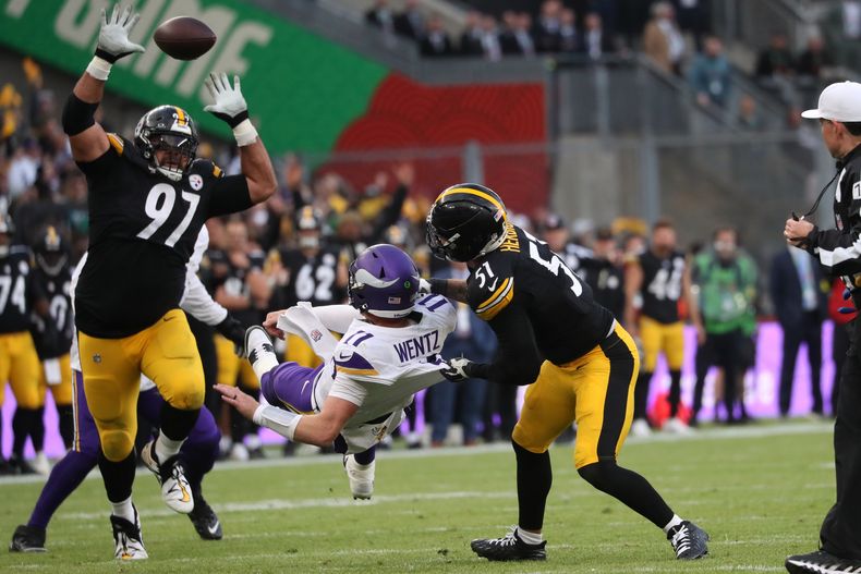 Cameron Heyward (97), izquierda, tackle defensivo de los Steelers de Pittsburgh, Nick Herbig (51) y el quarterback de los Vikings de Minnesota Carson Wentz (11), centro, pone el balón en el aire en riesgo de ser robado por los defensivos de Pittsburgh, durante el partido de la NFL entre los Vikings de Minnesota y Steelers de Pittsburgh, en el estadio Croke Park en Dublin, el domingo 28 de septiembre de 2025. (AP Foto/Peter Morrison)