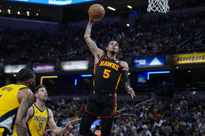 ARCHIVO- Dejounte Murray (5), de los Hawks de Atlanta, se alza para retacar el balón frente a T.J. McConnell (9), de los Pacers de Indiana, durante la primera mitad del juego de baloncesto de la NBA en Indianápolis, el 14 de abril de 2024. Atlanta está cerrando pláticas para intercambiar al anotador Dejounte Murray a los Pelicans de Nueva Orleans por un paquete que se espera que incluya a dos selecciones de primera ronda de draft. (AP Foto/Michael Conroy, Archivo)