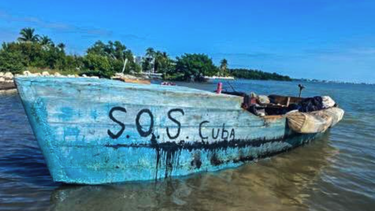 grupo de balseros cubanos llegan a eeuu en una embarcacion con la frase de ´sos cuba´