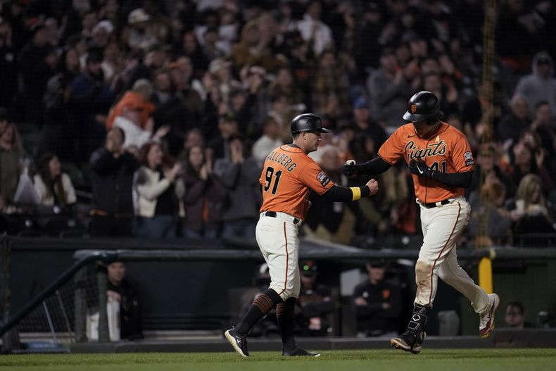 El venezolano Wilmer Flores, de los Gigantes de San Francisco, celebra con el coach de la antesala Mark Hallberg, luego de conectar un jonrón de dos carreras ante los Rockies de Colorado, en el juego del viernes 8 de septiembre de 2023 (AP Foto/Godofredo A. Vásquez)