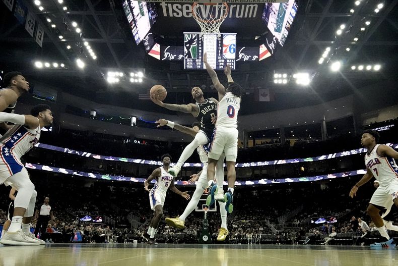 Damian Lillard de los Bucks de Milwaukee lanza el balón superando a Tyrese Maxey de los 76ers de Filadelfia en el encuentro de la NBA del jueves 14 de marzo del 2024. (AP Foto/Morry Gash)