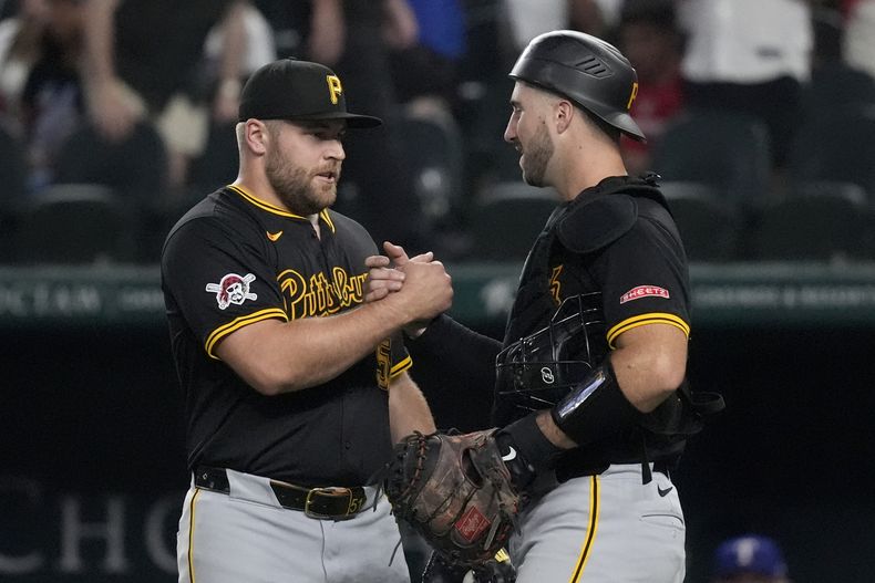 El lanzador relevista de los Piratas de Pittsburgh, David Bednar, a la izquierda, y el receptor Joey Bart, a la derecha, celebran la victoria del equipo por 4-0 contra los Rangers de Texas, el martes 20 de agosto de 2024, en Arlington, Texas. (AP Foto/LM Otero)