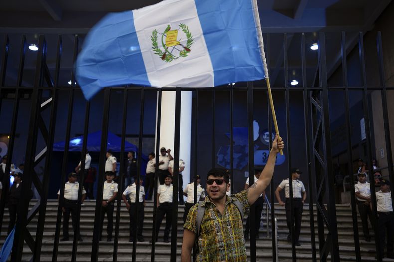 Un manifestante ondea una bandera guatemalteca frente al edificio de la oficina del Fiscal General para mostrar su apoyo al proceso electoral y al avance de la segunda vuelta de las elecciones presidenciales en Ciudad de Guatemala, el viernes 14 de julio de 2023. (Foto AP/Moisés Castillo)