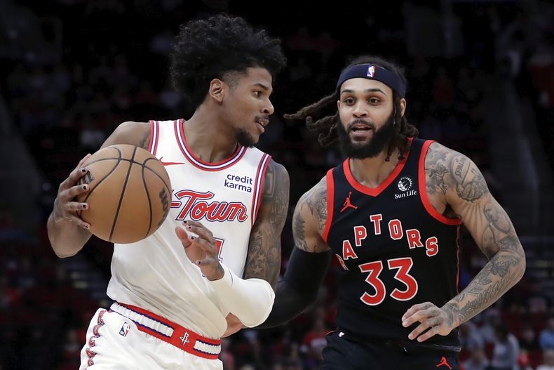 Jalen Green, izquierda, de los Rockets de Houston, lleva el balón alrededor de Gary Trent Jr. (33), de los Raptors de Toronto, durante la primera mitad del juego de baloncesto de la NBA, el viernes 2 de febrero de 2024, en Houston. (AP Foto/Michael Wyke)