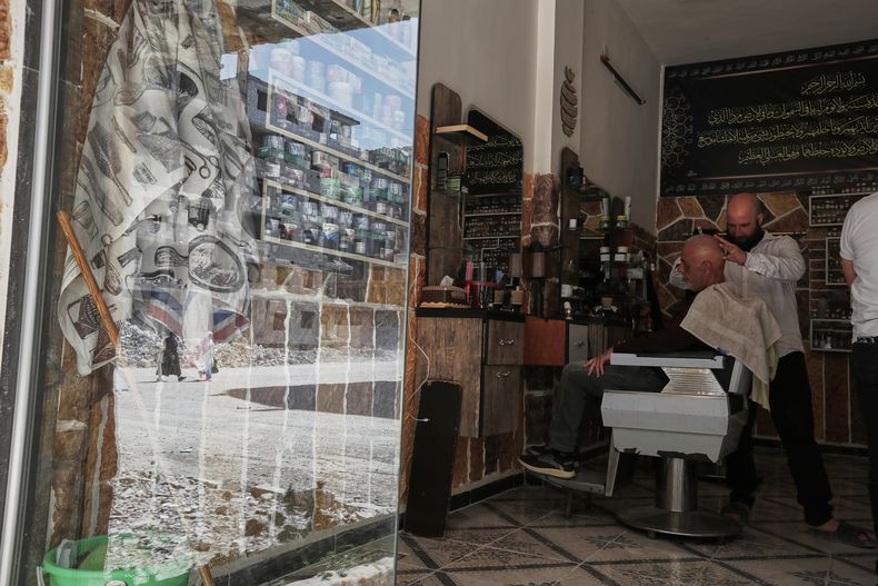 Un barbero rasura a un cliente en su barbería recién inaugurada en Daraya, Siria, el lunes 17 de marzo de 2025. Daraya es parte de la zona rural de Damasco y fue uno de los centros del levantamiento contra Bashar Assad, por lo que sufrió asesinatos y enormes daños durante los combates. (AP Foto/Omar Sanadiki)