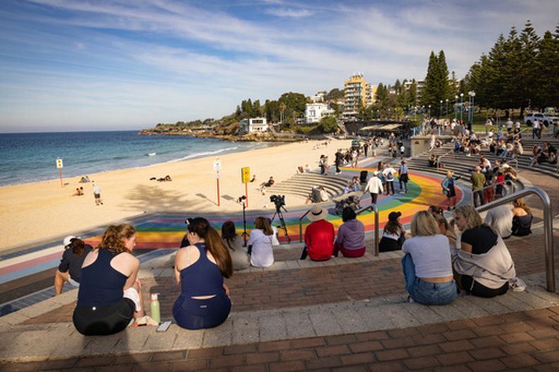 Varias personas, sentadas en las escaleras frente a la playa de Coogee tras el ataque de un tiburón, en Sydney, el 13 de junio de 2026. (Nadir Kinani/AAP Image vía AP)