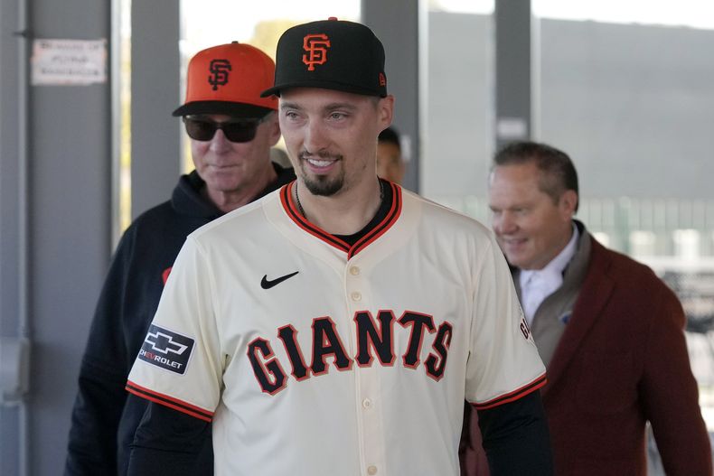 El nuevo lanzador de los Gigantes de San Francisco Blake Snell (centro) camina junto al mánager de los Gigantes Bob Melvin (izquierda), y el agente de Snell Scott Boras (derecha), previo a ser presentado en la conferencia de prensa, el miércoles 20 de marzo, en Scottsdale, Arizona. (AP Foto/Ross D. Franklin)