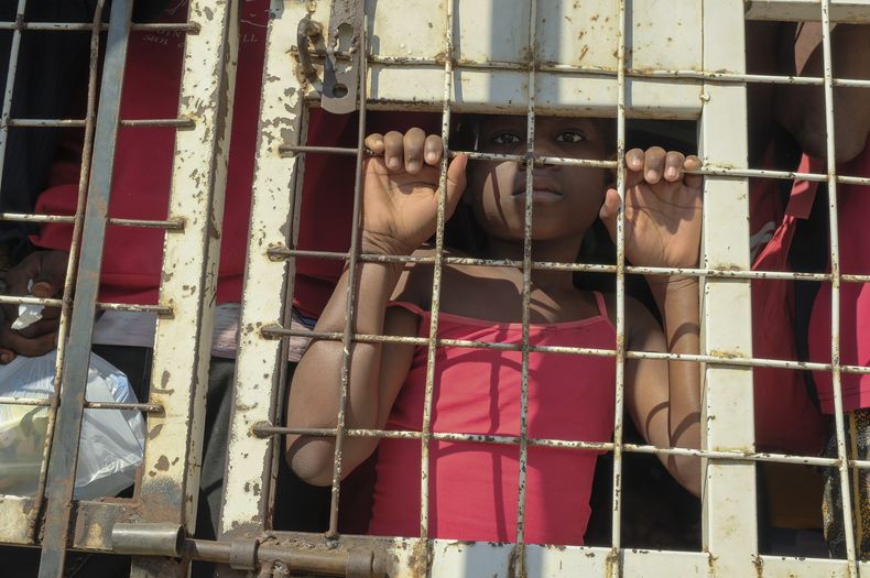 Un niño junto con personas detenidas para ser deportadas hacia Haití, en un camión policial, en un puente que conecta a Dajabón, República Dominicana, con Haití, el 18 de marzo de 2024. (Foto AP/Ricardo Hernandez)