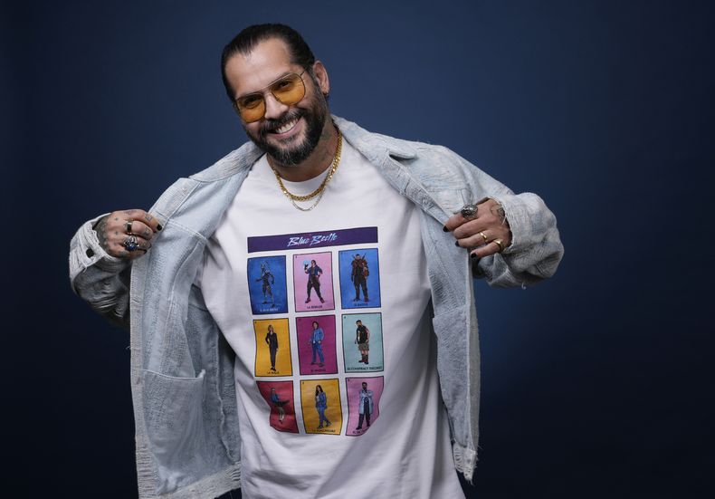Ángel Manuel Soto, director de Blue Beetle, muestra una camiseta con el elenco de la película al posar para un retrato el 4 de agosto de 2023, en el Hotel London en West Hollywood, California. El elenco no pudo promover la película por la huelga de actores de Hollywood. (Foto AP/Chris Pizzello)