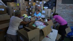 Tres voluntarias organizan cajas con juguetes usados en la organización sin fines de lucro Hospital de los Peluches, en donde recuperan y reparan juguetes usados para donarlos a niños vulnerables como regalos de Navidad, en Caracas, Venezuela, el jueves 5 de diciembre de 2024. (AP Foto/Ariana Cubillos)
