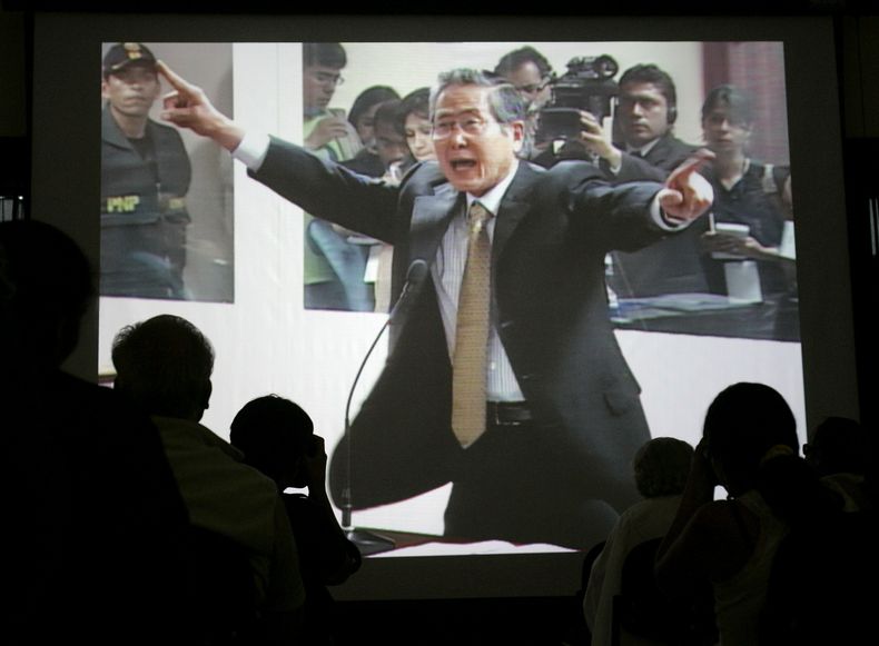 ARCHIVO - El expresidente de Perú Alberto Fujimori captado gesticulando en una pantalla el primer día del juicio en el que enfrenta cargos por violaciones a los derechos humanos y corrupción durante su gobierno en una sede policial en Lima, el 10 de diciembre de 2007. Su hija, Keiko Fujimori, informó el miércoles 11 de septiembre de 2024 que el exmandatario falleció de cáncer a los 86 años. (AP Foto/Martín Mejía, Archivo)