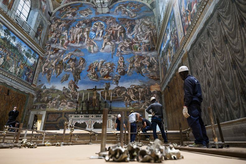 En esta imagen del lunes 28 de abril de 2025, varios trabajadores preparan la capilla Sixtina en el Vaticano, donde comenzará el próximo cónclave el 7 de mayo, ante el fresco de Miguel Ángel El juicio final. (Vatican Media vía AP)