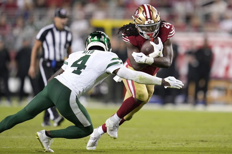 El runningback de los 49ers de San Francisco, Jordan Mason (derecha) corre ante el cornerback de los Jets de Nueva York, D.J. Reed (4) durante la segunda mitad del juego de NFL en Santa Clara, California, el lunes 9 de septiembre de 2024. (AP Foto/Godofredo A. Vásquez)