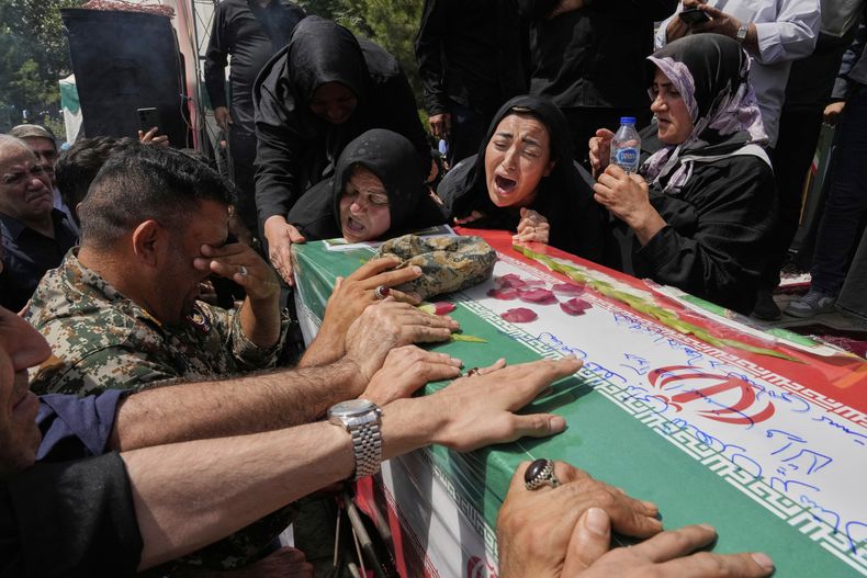 Parientes lloran sobre el ataúd cubierto por una bandera de Mahan Setareh, miembro de la fuerza paramilitar Basij, fallecido en ataques israelíes, durante su funeral en Teherán, Irán, el jueves 26 de junio de 2025. (AP Foto/Vahid Salemi)