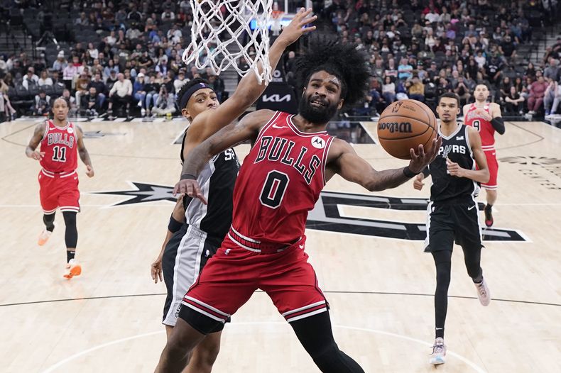 Coby White (0), de los Bulls de Chicago, anota después de superar a Keldon Johnson (3), de los Spurs de San Antonio, durante la segunda mitad del juego de baloncesto de la NBA, en San Antonio, el viernes 8 de diciembre de 2023. (AP Foto/Eric Gay)