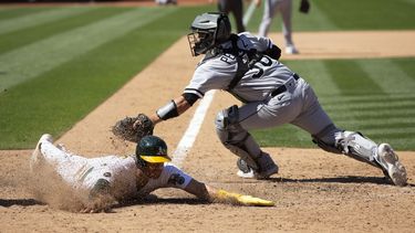 Tyler Wade de los Atléticos de Oakland se desliza en el plato para la carrera de la victoria frente al cátcher de los Medias Blancas de Chicago Carlos Pérez en la décima entrada el sábado 1 de julio del 2023. (AP Foto/D. Ross Cameron)