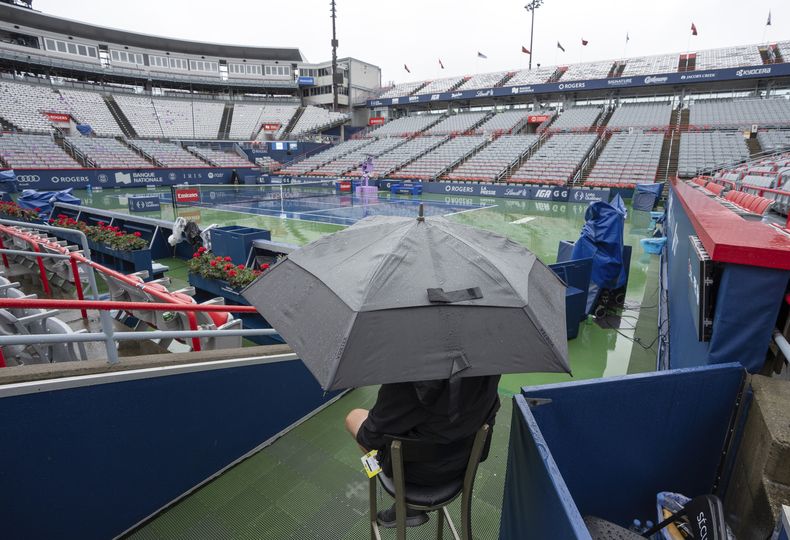 Un agente de seguridad sentado bajo una sombría mientras llueve durante el Abierto de Montreal el viernes 9 de agosto del 2024. (yan Remiorz/The Canadian Press via AP)
