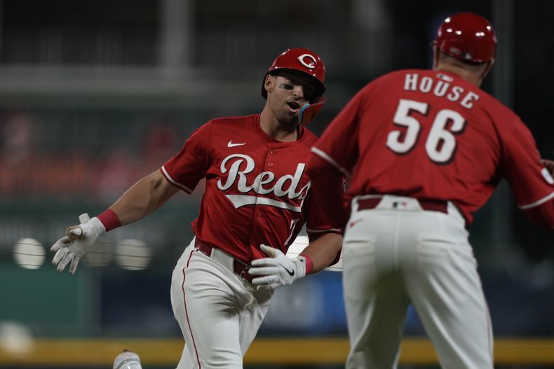 Spencer Steer, izquierda, de los Rojos de Cincinnati, celebra con el coach de tercera base J.R. House mientras recorre las bases después de batear un cuadrangular de dos carreras en la primera entrada del juego de béisbol de Grandes Ligas ante los Mellizos de Minnesota, el miércoles 18 de junio de 2025, en Cincinnati. (AP Foto/Carolyn Kaster)