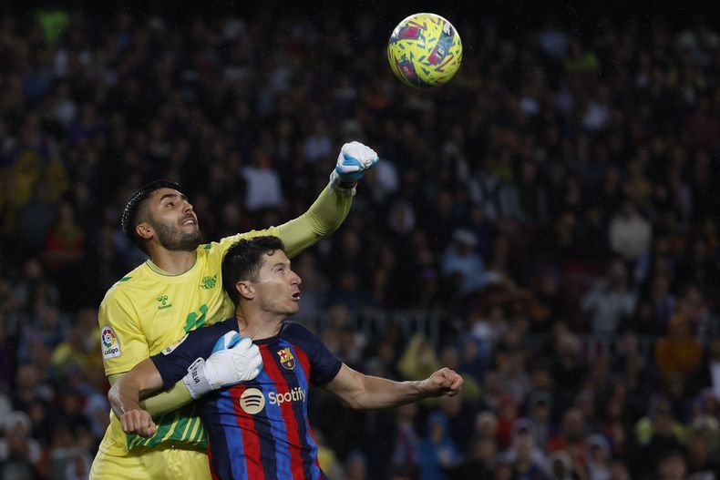 El arquero Rui Silva (izquierda) del Betis despeja el balón frente a Robert Lewandowski del Barcelona en el partido de la Liga española, el sábado 29 de abril de 2023, en Barcelona. (AP Foto/Joan Monfort)