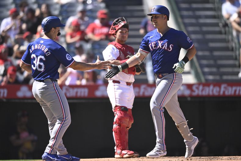 Nathaniel Lowe, de los Rangers de Texas, a la derecha, es felicitado por Wyatt Langford después de conectar un jonrón durante la octava entrada contra los Angelinos de Los Ángeles, el domingo 29 de septiembre de 2024, en Anaheim, California (AP Foto/John McCoy)