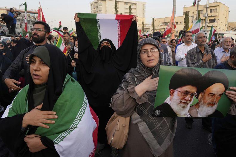 Manifestantes iraníes sostienen banderas del país y un cartel del ayatolá Jomeini, el fallecido líder revolucionario iraní, a la derecha, y el actual líder supremo, el ayatolá Alí Jamenei, en una protesta contra Estados Unidos e Israel en la plaza Enqelab-e-Eslami (Revolución Islámica) en el centro de Teherán, Irán, el martes 24 de junio de 2025. (AP Foto/Vahid Salemi)