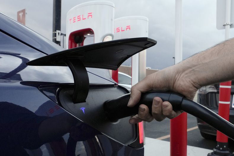 ARCHIVO – Un conductor carga su vehículo eléctrico en una estación de carga de Tesla en Detroit, el 16 de noviembre de 2022. (AP Foto/Paul Sancya, Archivo)