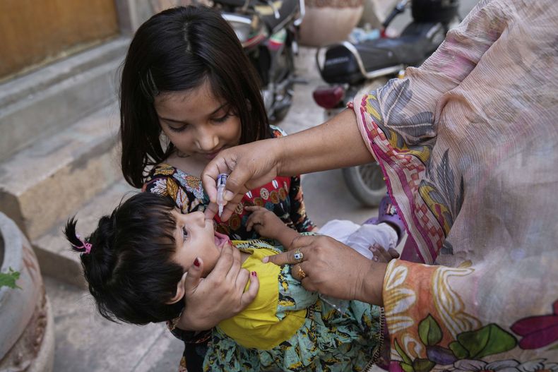 Una trabajadora de salud administra una vacuna contra la polio a una niña en un vecindario en en Lahore, Pakistán, el lunes 26 de mayo de 2025. (AP Foto/K.M. Chaudary)
