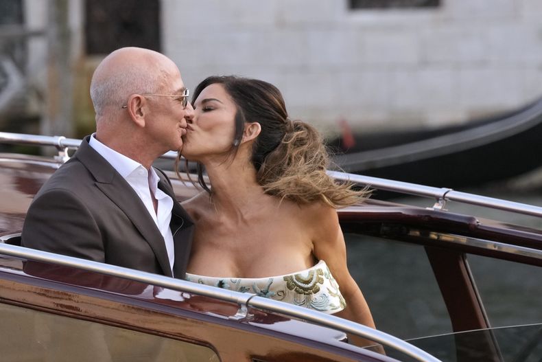 Jeff Bezos, a la izquierda, y Lauren Sanchez se besan al salir de un hotel previo a su boda, en Venecia, Italia, el jueves 26 de junio de 2025. (Foto AP/Luca Bruno)