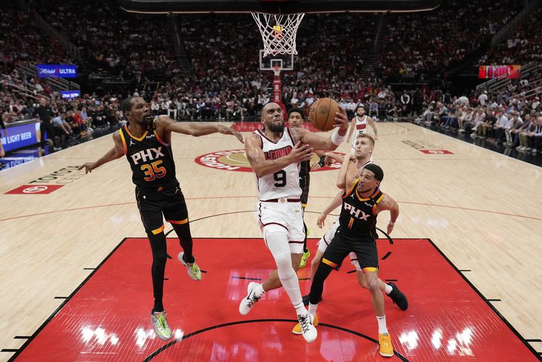 Dillon Brooks de los Rockets de Houston salta para anotar dejando atrás a Kevin Durant y Devin Booker de los Suns de Phoenix en el encuentro de la NBA del miércoles 12 de marzo del 2025. (AP Foto/David J. Phillip)