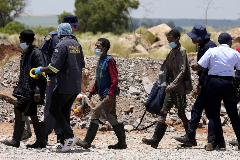 Policías escoltan a mineros ilegales después de ser rescatados de una mina de oro abandonada donde pasaron meses en Stilfontein, Sudáfrica, el 14 de enero de 2025. (AP Foto/Themba Hadebe)