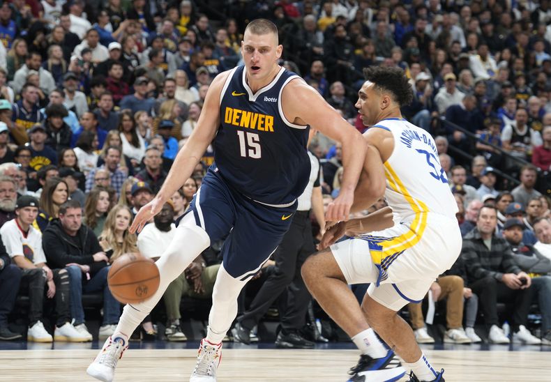 El serbio Nikola Jokic, de los Nuggets de Denver, elude a Trayce Jackson-Davis, alero de los Warriors de Golden State, en el encuentro del miércoles 8 de noviembre de 2023 (AP Foto/David Zalubowski)