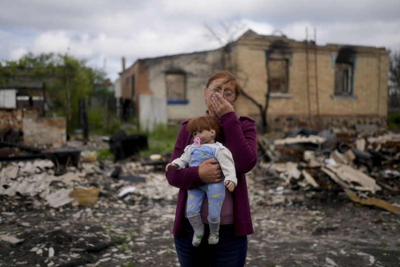 Nila Zelinska carga una muñeca que era de su nieta y que logró encontrar en su casa destruida en Potashnya, en las afueras de Ucrania, el martes 31 de mayo de 2022. Zelinska acaba de regresar a su pueblo después de escapar de la guerra para enterarse que ya no tiene casa. (AP Foto/Natacha Pisarenko)