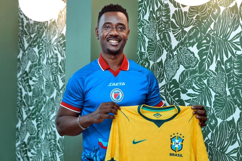 El aficionado francés Peguy Joseph sostiene una camiseta de la selección de Francia mientras lleva puesta la de Haití al posar para una foto, el 22 de mayo de 2026, en Ellenton, Florida. (AP Foto/Chris OMeara)