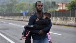 Un migrante carga a un niño por Tapachula, estado de Chiapas, México, el jueves 2 de enero de 2025, como parte de una caravana de migrantes que intentan llegar a la frontera con Estados Unidos. (AP Foto/Edgar H. Clemente)