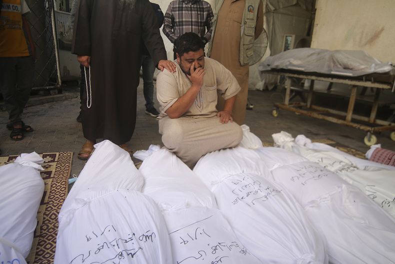 Varios palestinos se lamentan junto a los cuerpos de la familia Awaja, que murió por un bombardeo israelí en la Franja de Gaza, el viernes 20 de octubre de 2023, en Rafah. (AP Foto/Hatem Ali)
