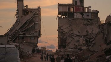 Varios palestinos caminan por una calle rodeada por edificios destruidos pr ataques militares israelíes durante la guerra entre Israel y Hamás en Ciudad de Gaza, el martes 6 de octubre de 2026. (AP Foto/Jehad Alshrafi)