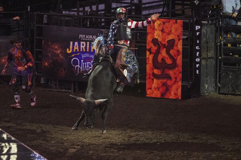 Un miembro del equipo vaquero monta un toro en el espectáculo Jaripeo hasta los huesos tour 2024 de Pepe Aguilar en el Honda Center en Anaheim, California, el viernes 29 de marzo de 2024. El espectáculo rinde homenaje al Día de Muertos, una conocida celebración mexicana. (Foto AP/Damian Dovarganes)