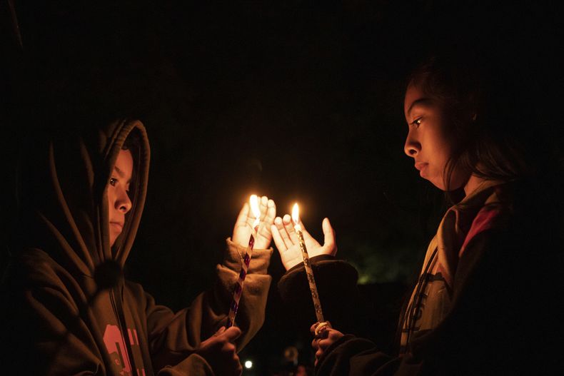 Jóvenes sostienen velas sobre una tumba en un cementerio en Atzompa, México, el martes 31 de octubre de 2023 por la noche. (AP Foto/María Alferez)