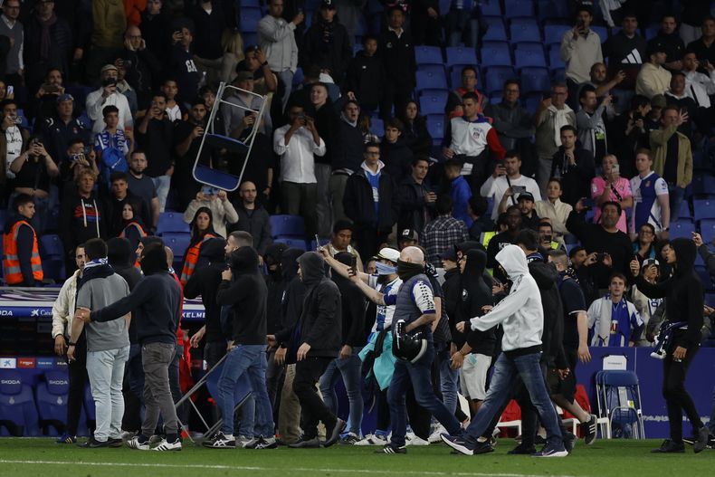 Seguidores del Espanyol saltan a la cancha y lanzan objetos después de que el Barcelona vencieran al Espanyol y confirmara el título de liga el domingo 14 de mayo del 2023. (AP Foto/Joan Monfort)