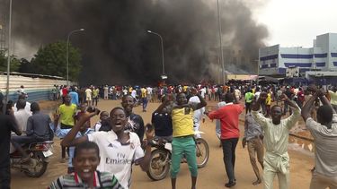 Con la sede del gobierno ardiendo de fondo, partidarios de los soldados amotinados se manifiestan en Niamey, Níger, el 27 de julio de 2023. (AP Foto/Fatahoulaye Hassane Midou)