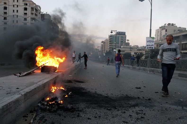 Manifestantes opuestos a la Hermandad Musulmana pasan junto a una barricada en llamas en el distrito de Ciudad Nasr, en El Cairo, Egipto, el viernes 22 de noviembre del 2013.(Foto AP/Diario El-Shorouk, Sabry Khaled)