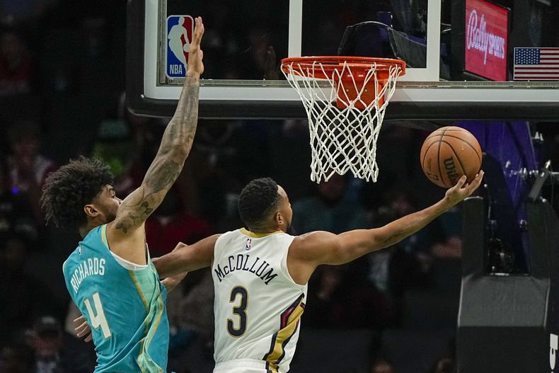 CJ McCollum, base de los Pelicans de Nueva Orleáns, encesta frente a Nick Richards, de los Hornets de Charlotte, el viernes 15 de diciembre de 2023 (AP Foto/Chris Carlson)