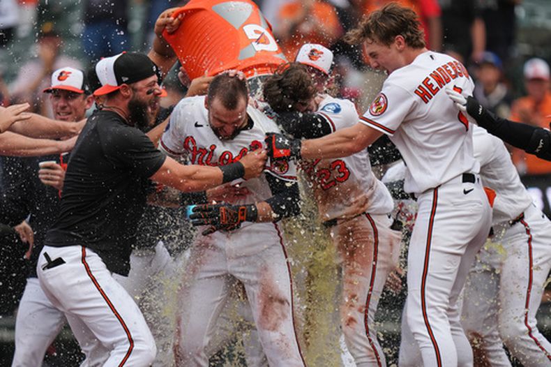 Colton Cowser, centro, de los Orioles de Baltimore, celebra con sus compañeros de equipo después de batear un cuadrangular de dos carreras para dejar tendidos en el campo a los Rays de Tampa Bay en 13 entradas, el lunes 25 de mayo de 2026, en Baltimore. (AP Foto/Stephanie Scarbrough)